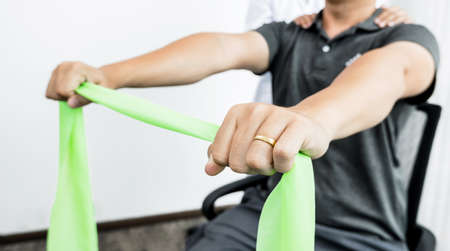 Female physiotherapists are helping male patients with arm injuries, arms pulling, muscle relaxation...