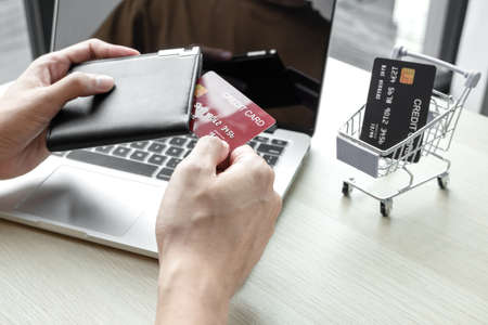 The businessman's hand is holding a credit card and using a laptop for online shopping and internet payment in the office.の写真素材