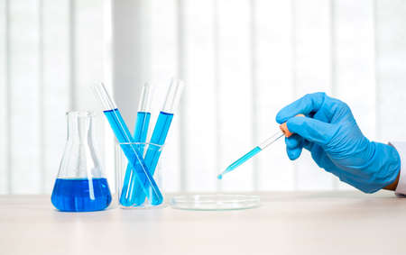 Medical scientists released a sample pipetted into test glassware to analyze the virus in a chemical...