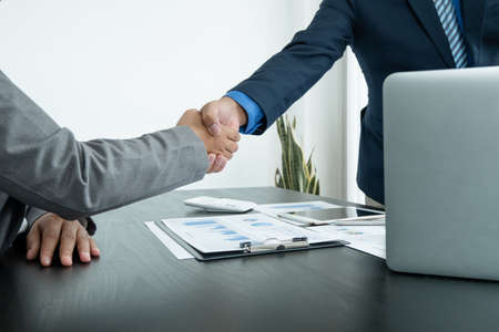 Shaking hand two business leaders talk about charts, financial graphs showing results are analyzing and calculating planning strategies, business success building processes.の写真素材