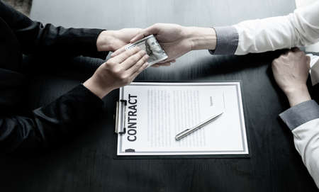 A photo of a businessman who gives money to his partner to bribe the idea of ââbribery and corruption.の写真素材