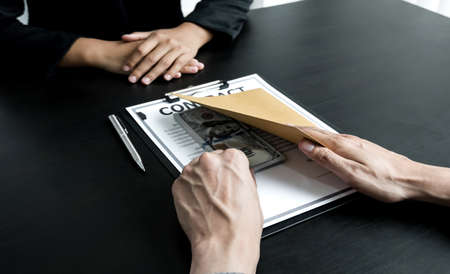 Businessmen make an agreement with the money proposed by his partner to bribe in the company. The concept of corruption.の写真素材
