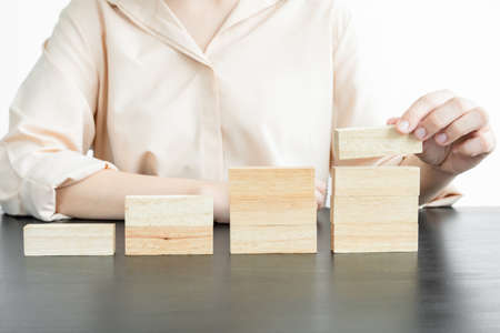 Hands of businesswomen playing wooden block game. Concept Risk of management and strategy plans for business growth and success.の写真素材
