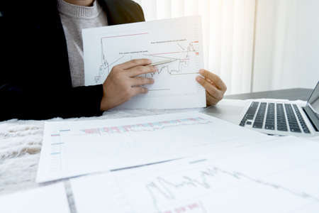 The hands of a female business brokerage are planning business investments by analyzing and...