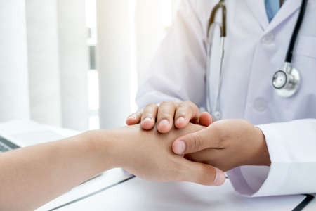 The female doctor uses a friendly hand to hold the patient's hand to give confidence and show care about health care. Medical concepts and good health.の写真素材