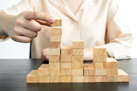 Hands of businesswomen playing wooden block game. Concept Risk of management and strategy plans for business growth and success.の写真素材