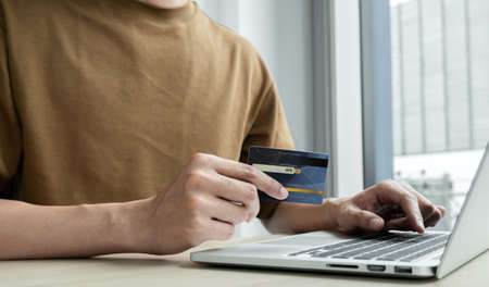 The businessman's hand is holding a credit card and using a laptop for online shopping and internet payment in the office.の写真素材