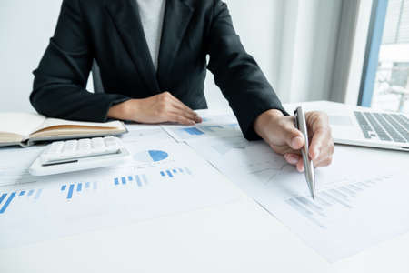 The hands of a male businesswoman are analyzing and calculating the annual income and expenses in a...
