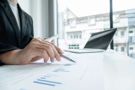 The hands of a male businesswoman use the calculator are analyzing and calculating the annual income...