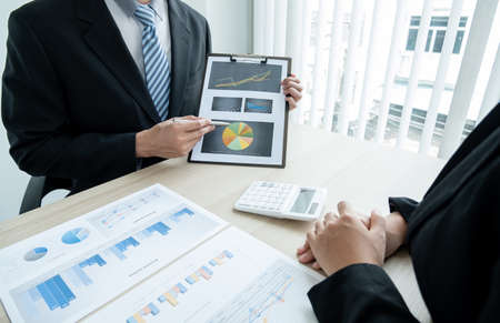 Two business leaders talk about charts, financial graphs showing results are analyzing and...
