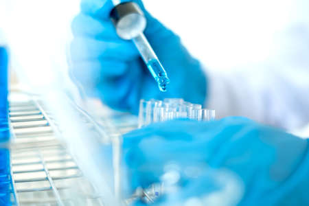 Medical scientists released a sample pipette into a test tube to analyze the virus in a chemical...