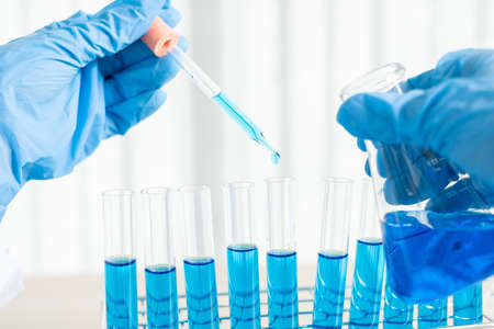 Medical scientists released a sample pipette into a test tube to analyze the virus in a chemical...