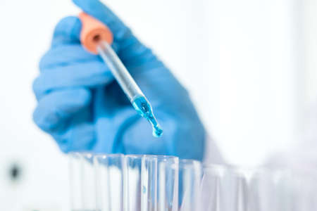 Medical scientists released a sample pipette into a test tube to analyze the virus in a chemical laboratory. Scientific research concepts.の写真素材