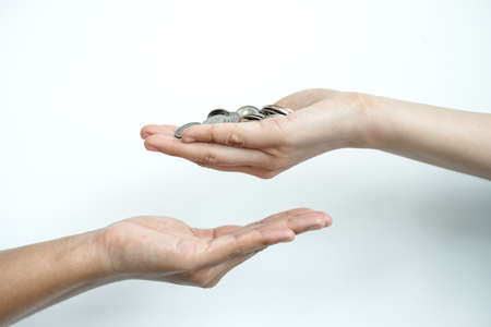 Hand holds a coin that gives the coin to the other hand. Money concept.