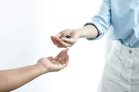Hand holds a coin that gives the coin to the other hand. Money concept.