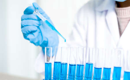 Medical scientists released a sample pipette into a test tube to analyze the virus in a chemical...