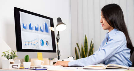 Asian woman working on a laptop with a cheerful and happy smile while working at the office.の写真素材