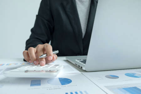 The hands of a male businesswoman use the calculator are analyzing and calculating the annual income...