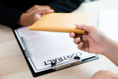 Businesswoman makes an agreement with money in an envelope proposed to a partner to bribe in the company. The concept of corruption.の写真素材