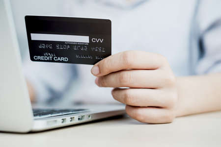 The businesswoman's hand is holding a credit card and using a laptop for online shopping and internet payment in the office.の写真素材