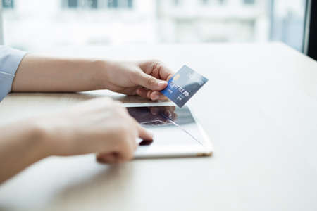 The businesswoman's hand is holding a credit card and using a laptop for online shopping and...