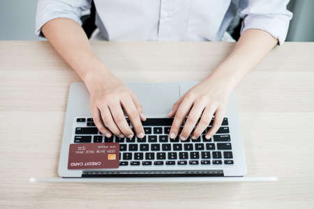 The businesswoman's hand is holding a credit card and using a laptop for online shopping and...
