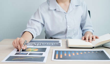 The hands of a male businesswoman are analyzing and calculating the annual income and expenses in a...