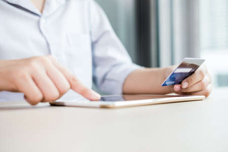 The businesswoman's hand is holding a credit card and using a laptop for online shopping and...
