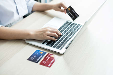 The businesswoman's hand is holding a credit card and using a laptop for online shopping and internet payment in the office.の写真素材