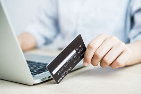 The businesswoman's hand is holding a credit card and using a laptop for online shopping and internet payment in the office.の写真素材