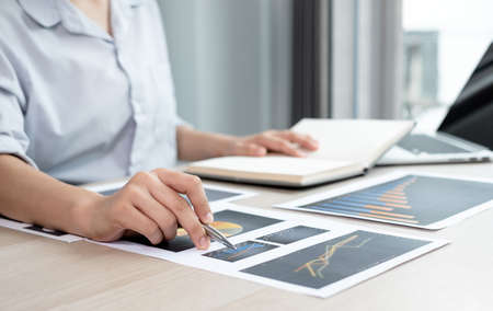 The hands of a male businesswoman are analyzing and calculating the annual income and expenses in a...