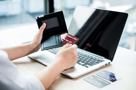 The businesswoman's hand is holding a credit card and using a laptop for online shopping and internet payment in the office.の写真素材