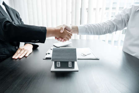 A real estate agent and clients shake hands after completing the home insurance contract negotiation and signing a formal contract. Rental and home insurance concepts.の写真素材