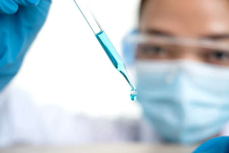 Medical scientists released a sample pipetted into test glassware to analyze the virus in a chemical laboratory. Scientific research concepts.の写真素材