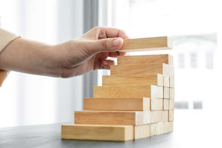 Hands of businesswomen playing wooden block game. Concept Risk of management and strategy plans for business growth and success.の写真素材