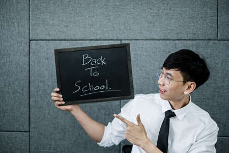 Back to school. Asian male students, holding blackboard labeled Back to School. College male Back to School after Pandemic Coronavirus Disease 2019.の写真素材