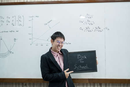 Back to school. Asian male students, holding blackboard labeled Back to School. College male Back to School after Pandemic Coronavirus Disease 2019.の写真素材