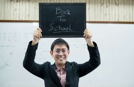 Back to school. Asian male students, holding blackboard labeled Back to School. College male Back to...
