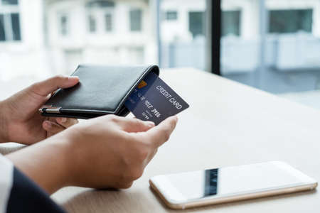 The businesswoman's hand is holding a credit card and using a smartphone for online shopping and internet payment in the office.の写真素材