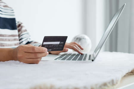 The businesswoman's hand is holding a credit card and using a laptop for online shopping and internet payment in the office.の写真素材