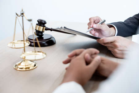 A male lawyer or a judge counseling clients about judicial justice and prosecution with scales, judges gavel, legal documents legal services concept.の写真素材