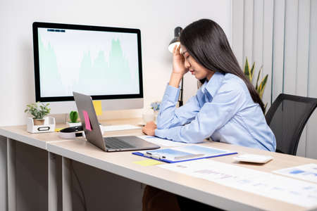 Working Asian women feel stressed, tired from work, migraine headaches from hard work while working...