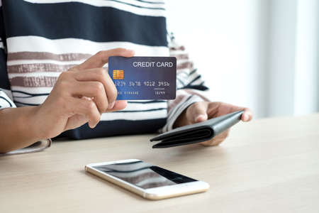 The businesswoman's hand is holding a credit card and using a smartphone for online shopping and...