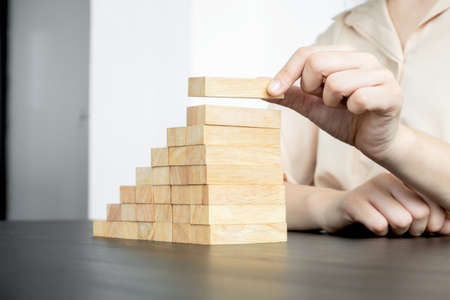 Hands of businesswomen playing wooden block game. Concept Risk of management and strategy plans for business growth and success.の写真素材