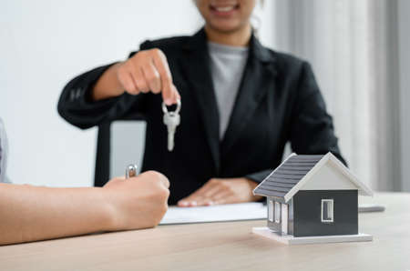 Real estate agent broker hand over the house key to the new owner after completing the signing according to agreement renting a house and buy house insurance Home insurance concept.の写真素材