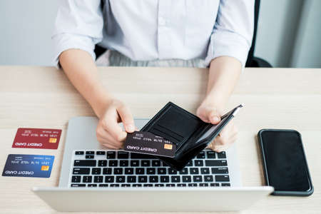 The businesswoman's hand is holding a credit card and using a laptop for online shopping and...