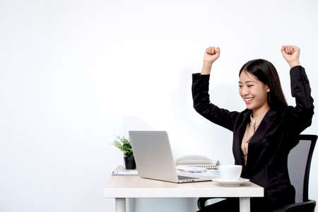 Asian businesswoman working on a laptop with a cheerful and happy smile while working at the office.の写真素材