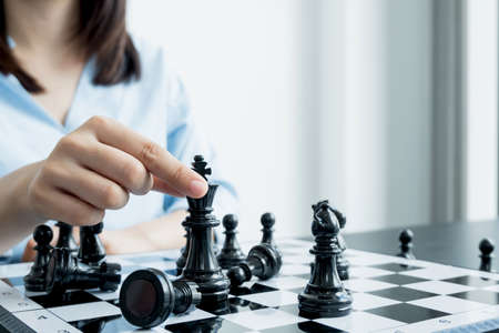 The hands of businesswomen moving chess in chess competitions demonstrate leadership, followers, and strategic plans, business success building processes, and teamwork.の写真素材
