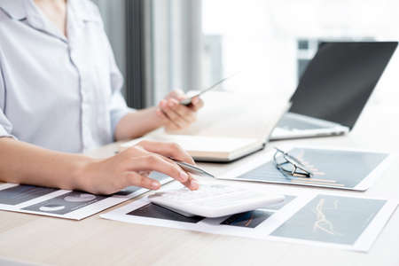 The hands of a male businesswoman are analyzing and calculating the annual income and expenses in a financial graph that shows results To summarize balances overall in office.の写真素材