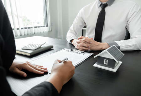 Real estate agents with house models are talking to customers about renting houses and buying home insurance. Rental and insurance concepts.の写真素材